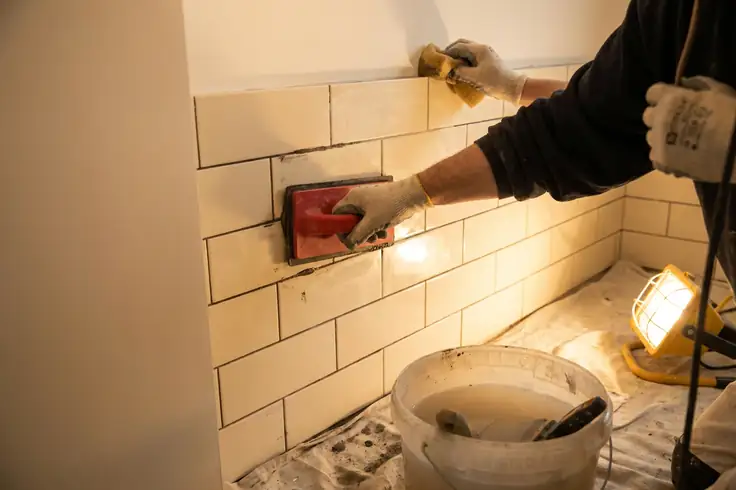 Réalisation des joints d’un carrelage mural de salle de bain à la raclette en caoutchouc